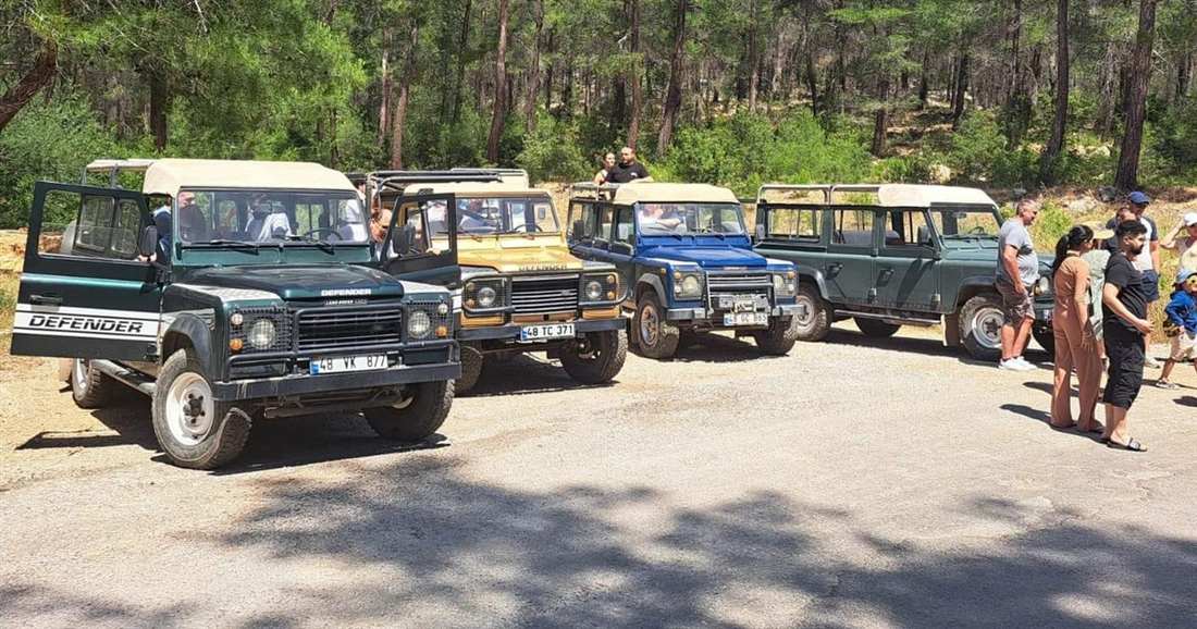 Open-top jeeps parked in a row at a pine forest stop on a jeep safari near Bodrum.