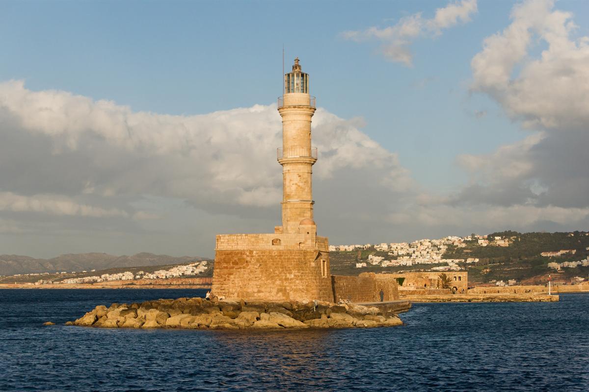 The stone lighthouse at the entrance to the Venetian harbour of Chania in the evening sun, a stop on a Chania shore excursion from Souda port.