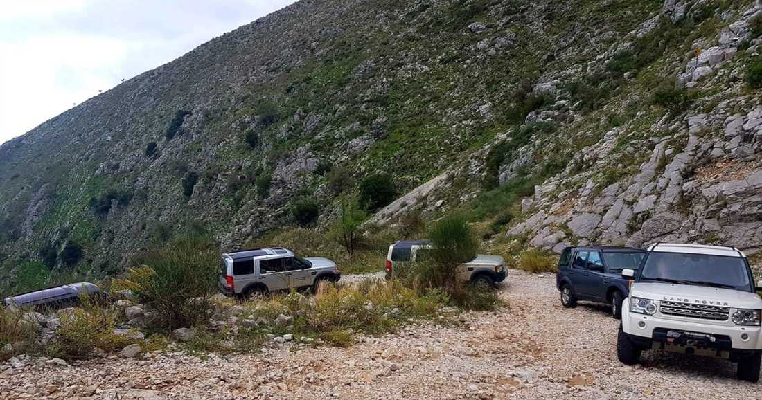 Land Rovers parked on a gravel mountain track below a rocky slope in north-west Corfu, on a Corfu jeep safari.