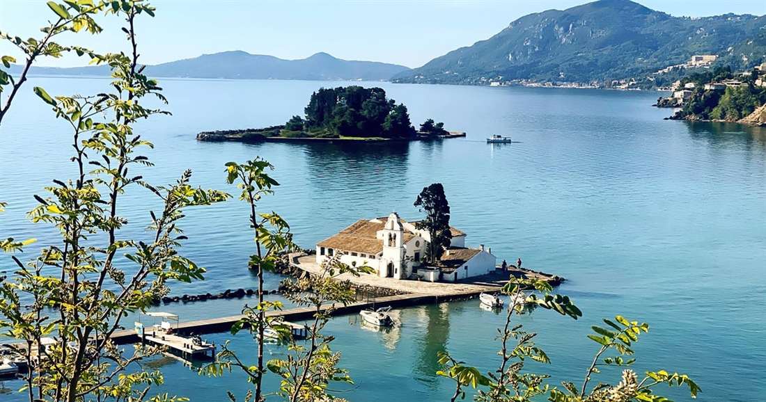 Vlacherna Monastery on its causeway and the wooded islet of Pontikonisi behind it, the ship turned to stone in the legend told on a Corfu mythology tour.