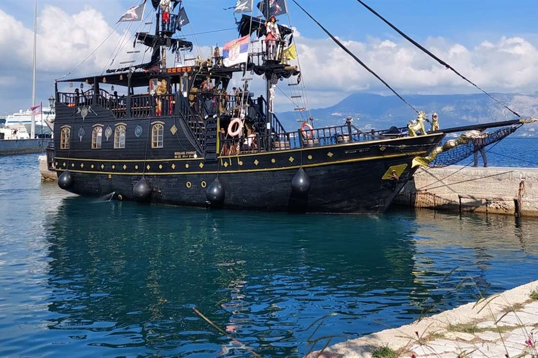 The Black Rose pirate ship with flags on its masts, moored in the harbour of Corfu Town, the Corfu pirate ship.