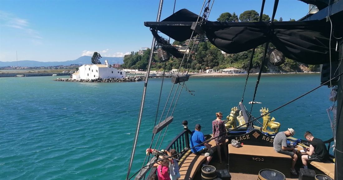 Guests on the deck of the Corfu pirate ship sailing past Vlacherna Monastery and Mouse Island.