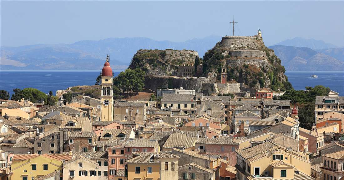 The Old Fortress and the rooftops of Corfu Old Town with the bell tower of Saint Spyridon, the first stop of a Corfu shore excursion from the cruise port.