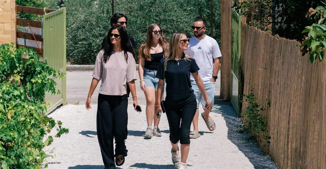 Guests walking up the gravel path into the farmhouse garden of a Corinth cooking class