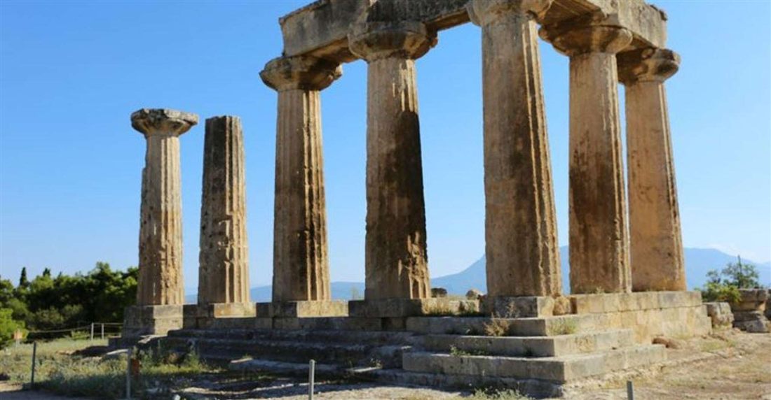 The Doric columns of the Temple of Apollo at Ancient Corinth under a blue sky