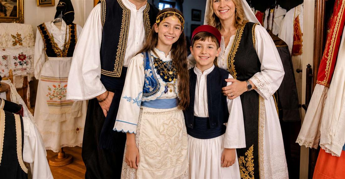 A family in Greek traditional costumes posing among embroidered folk dresses at a costume photo session