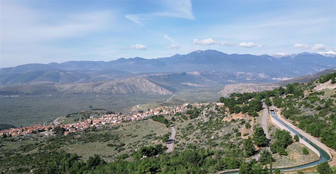The olive groves of the Pleistos valley below Delphi with the mountains of the Gulf of Corinth coast under a bright sky