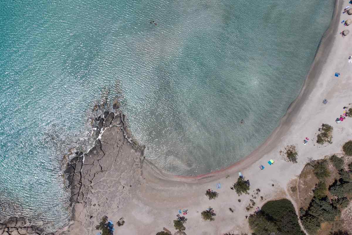 Aerial view of the curved pink-edged beach and turquoise shallows at Elafonisi, the goal of an Elafonisi day trip from Heraklion