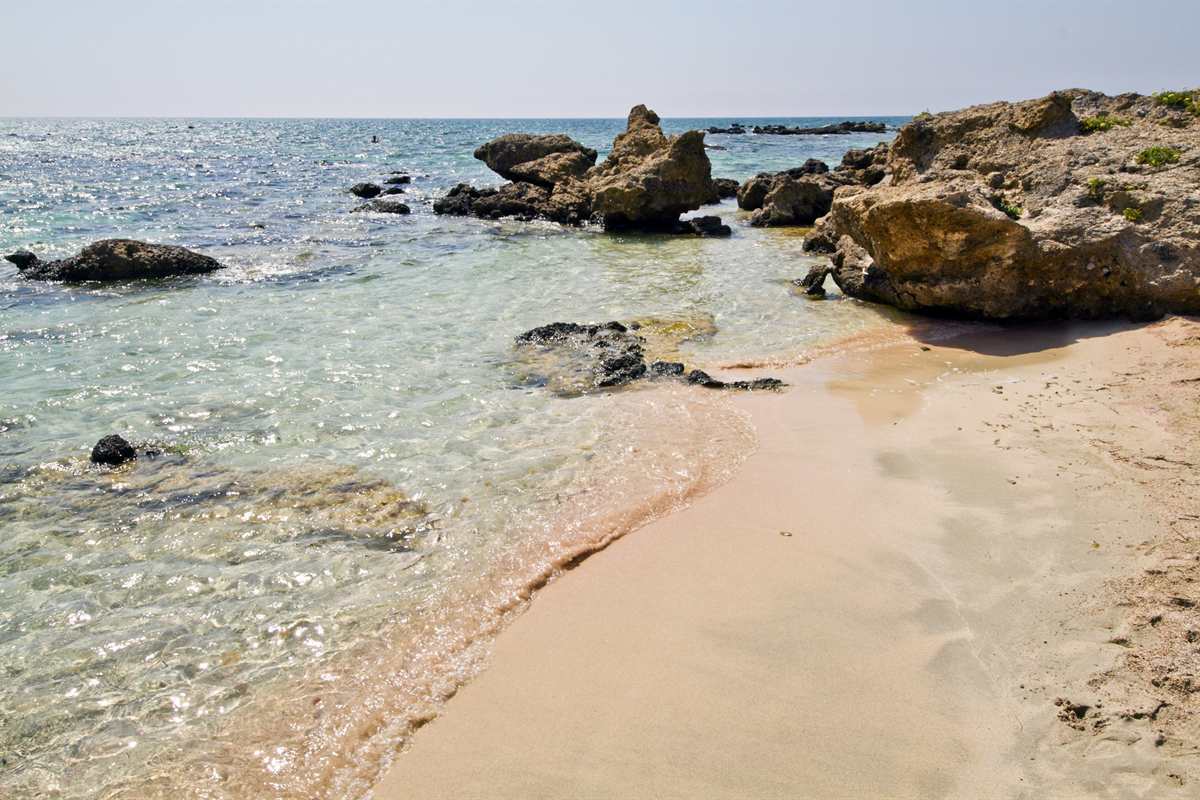 Pink-tinted sand and clear shallow water at Elafonisi, reached on an Elafonisi day trip from Rethymno