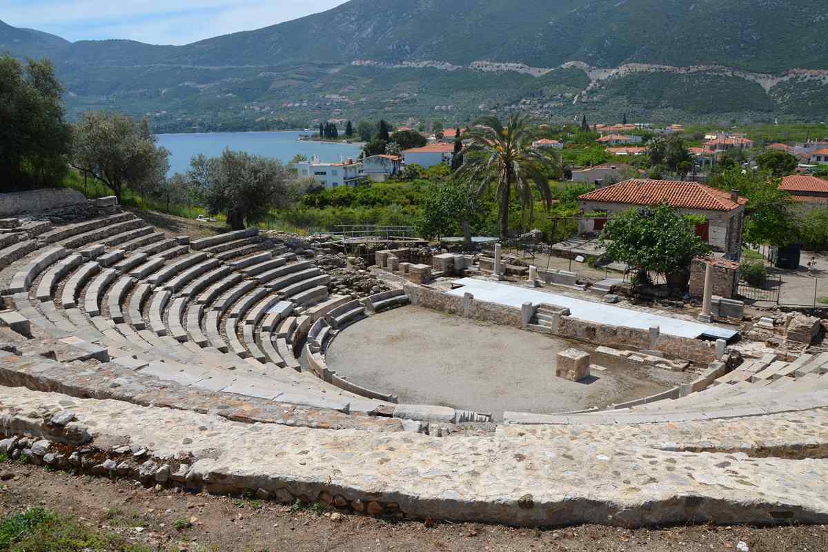 The Little Theatre of Palaia Epidavros with the bay and the village behind it, a stop on an Epidaurus tour that continues to the coast.