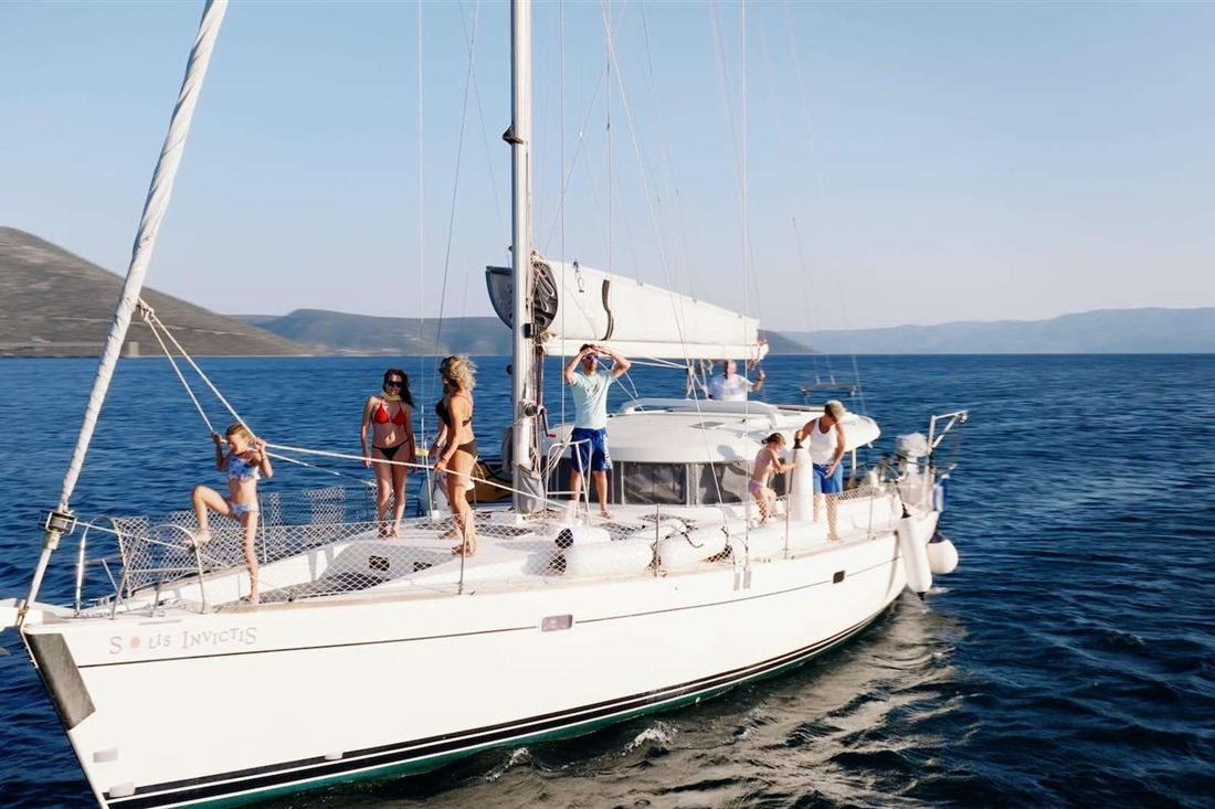 A white sailing yacht with guests on deck in the South Euboean Gulf