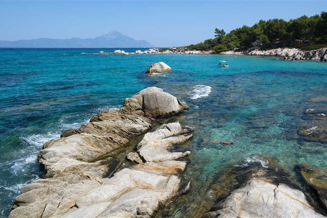 Turquoise water between smooth granite rocks at Kavourotrypes in Sithonia, one of the top Halkidiki snorkeling spots.