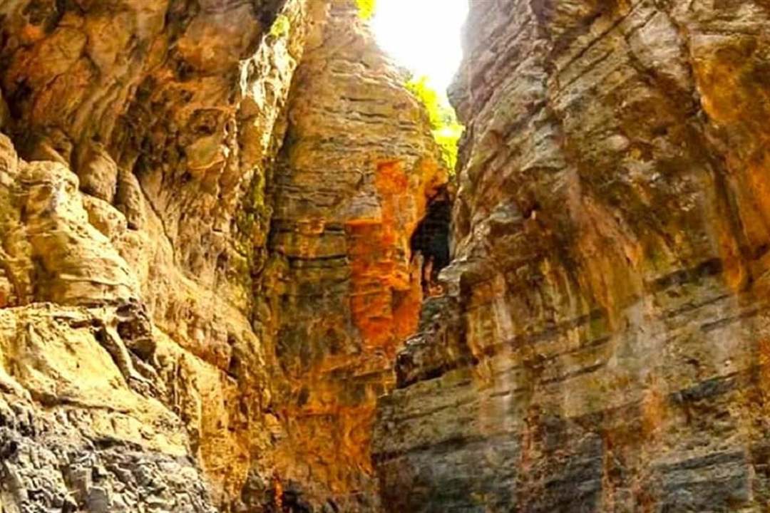 The narrowest stretch of the Imbros Gorge, with sheer golden rock walls rising on both sides of the path.