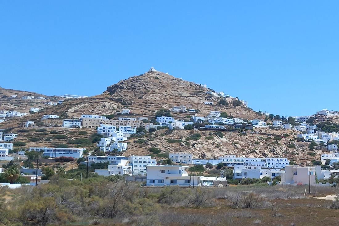 The whitewashed houses of Chora on Ios climbing a rocky hill topped by a chapel