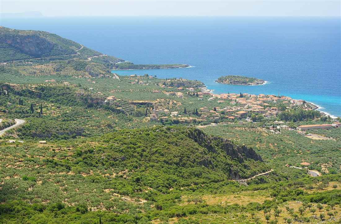 The coast of Kardamyli in the Mani with olive groves running down to a turquoise bay on the Messinian Gulf