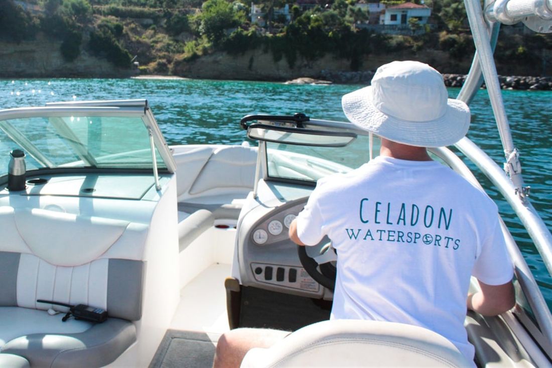 A skipper steering a speedboat across clear blue water towards a green coastline on a Kalamata snorkeling trip.