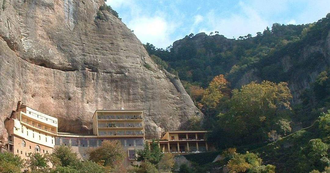 The Mega Spilaio monastery built against the foot of a tall rock face, above autumn trees near Kalavryta.
