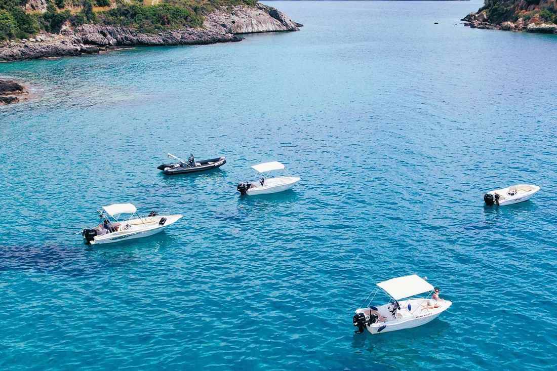 Small rental motorboats anchored in a turquoise bay on the Mani coast near Kardamyli