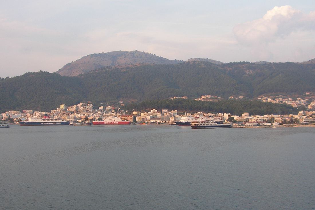 Ferries docked at Igoumenitsa port below the town and green hills, seen from the sea