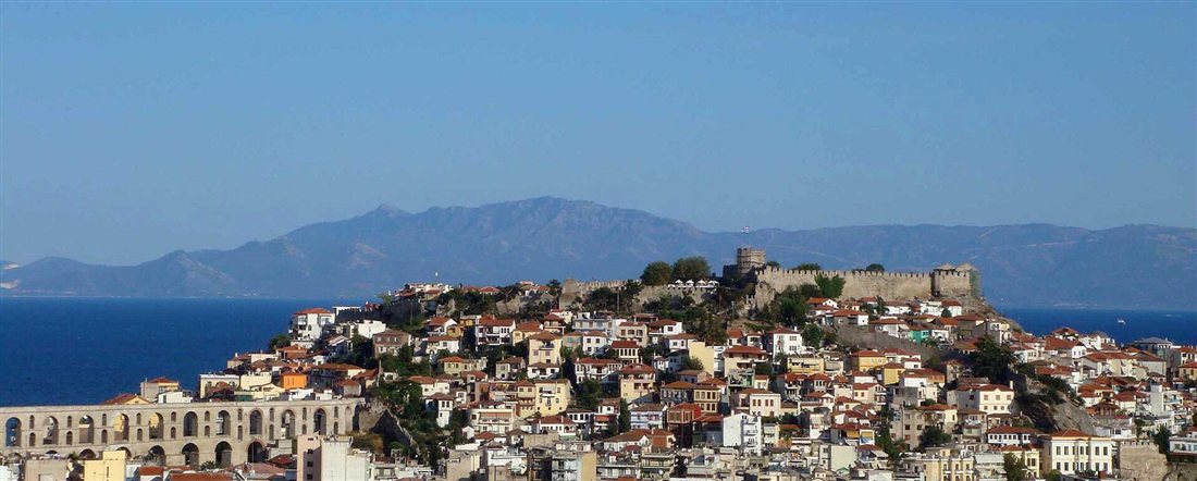 The arches of the Kamares aqueduct below the old town and castle of Kavala, with Thasos on the horizon