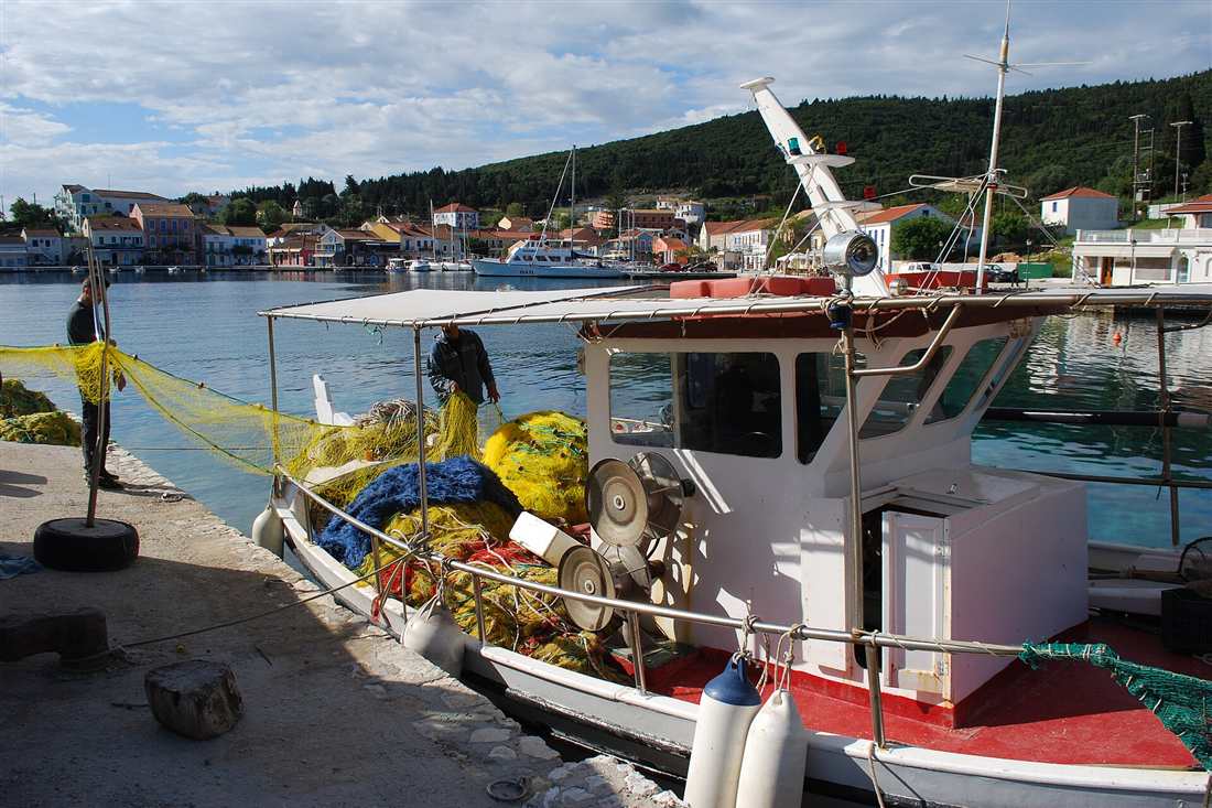 A fishing boat loaded with yellow and blue nets moored at the quay in Fiskardo, Kefalonia, the kind of boat used on a Kefalonia fishing trip.