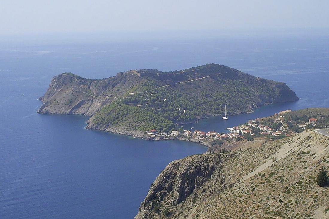 The green Assos peninsula on Kefalonia with its fortress walls and the small harbour village on the isthmus, seen from the coast road