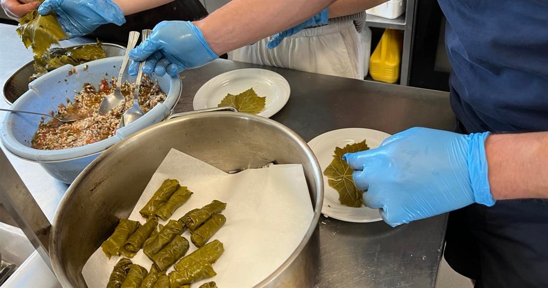Guests rolling vine leaves into dolmades and laying them in a pot at a Kos cooking class.