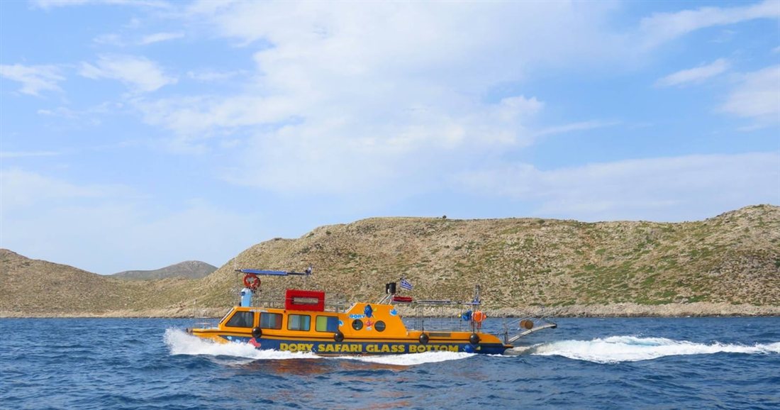 The yellow Dory Safari glass bottom speedboat cruising past the dry hills of the Kos coast.