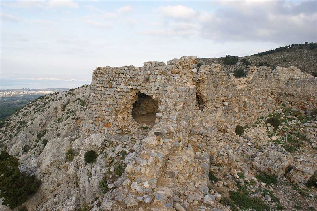 The ruined stone walls of the Byzantine castle of Old Pyli on a rocky hilltop on Kos, with the coast on the horizon