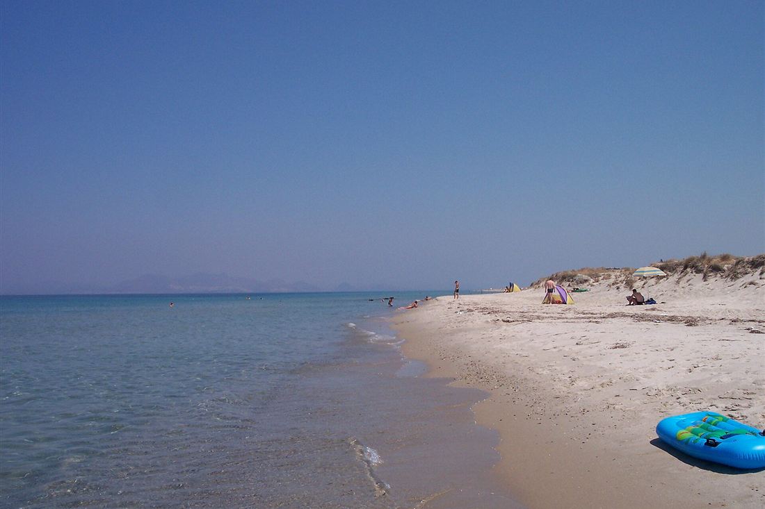 The shallow clear water and sandy beach by the salt lake on the north coast of Kos, a beach that pairs with a Kos water park day.