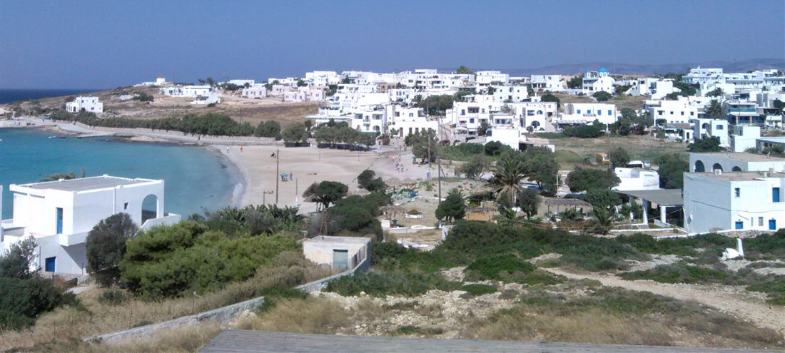 The white houses of Chora above the turquoise water and sand of Ammos beach on Pano Koufonisi, the island a Koufonisia boat trip reaches.