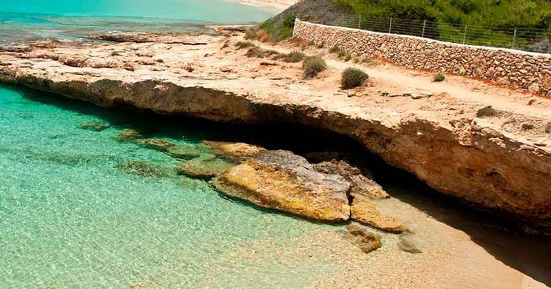 Clear turquoise water over pale rock shelves below a low sandstone cliff on Koufonisia.