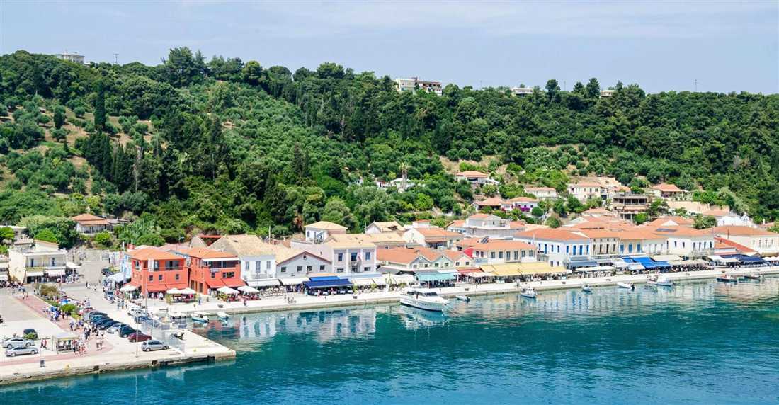 Harbour waterfront with colourful buildings, cafes, moored boats and a green wooded hill behind