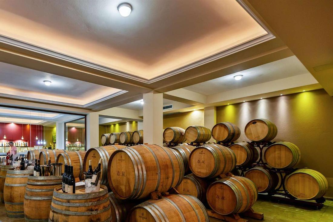 Oak wine barrels stacked in a winery cellar with wine bottles in ice buckets on barrel tops ready for tasting
