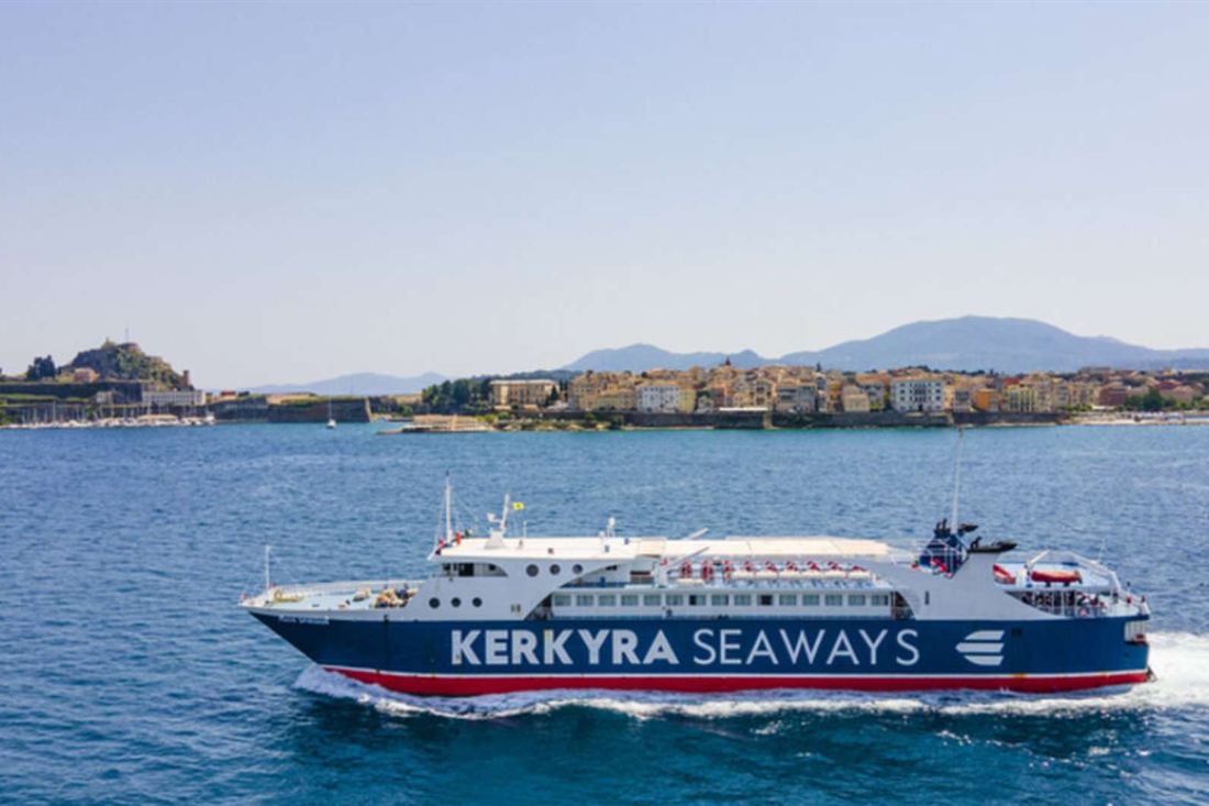 Blue and white Kerkyra Seaways ferry sailing across the blue sea in front of the old town and fortress of Corfu