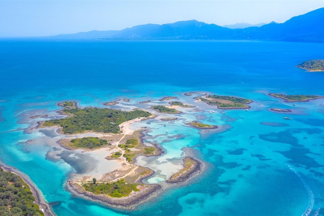 Aerial view of small green islets in shallow turquoise water, the Lichadonisia islets visited on a Lichadonisia boat trip.