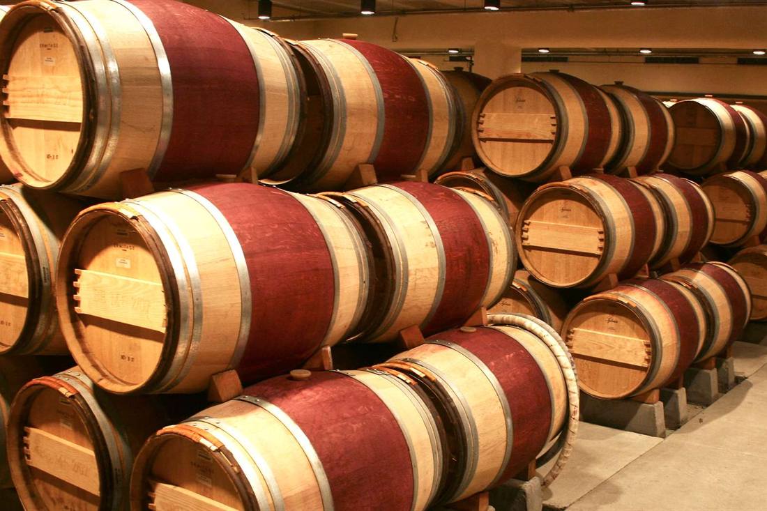 Rows of oak wine barrels stacked on wooden racks in a winery cellar