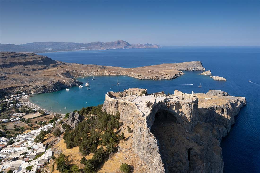 Aerial view of the Acropolis of Lindos on its rock, with St Paul's Bay and the coast of Rhodes behind.