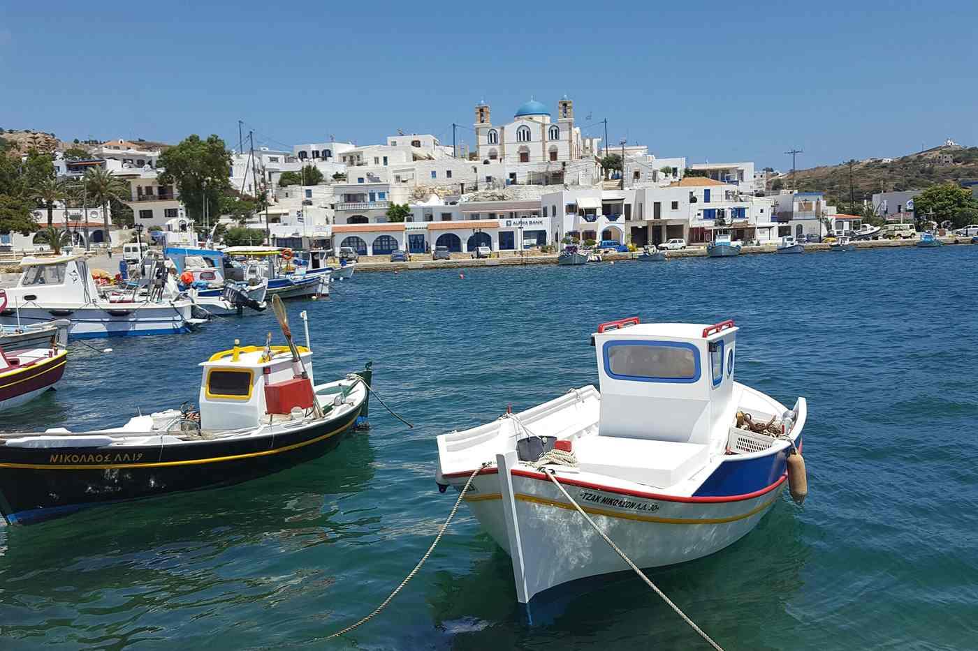 Lipsi harbour with fishing boats and the blue-domed church of Agios Ioannis above the village
