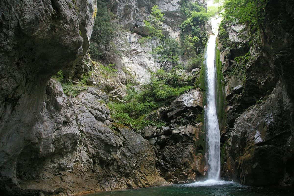 Litochoro tours on the Enipeas gorge trail reach a waterfall below Mount Olympus