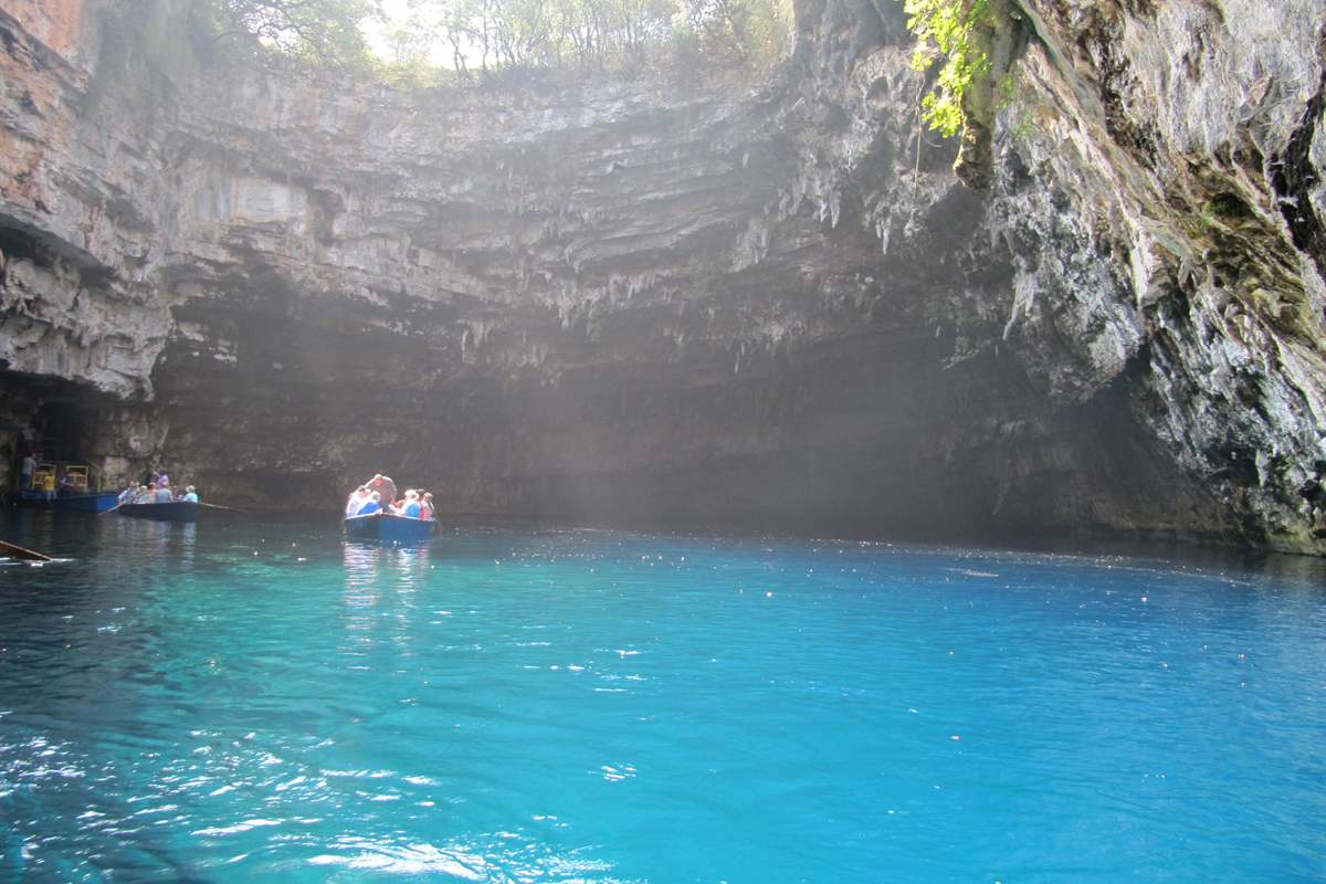 Rowing boats on the glowing blue lake under the open roof, the boat ride included in Melissani Cave tickets near Sami on Kefalonia