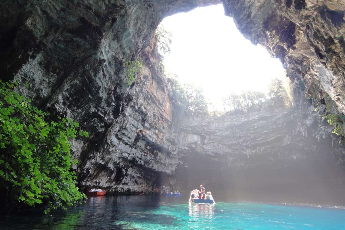 A rowing boat on the turquoise lake below the open roof, the view that Melissani Cave tickets show from the water