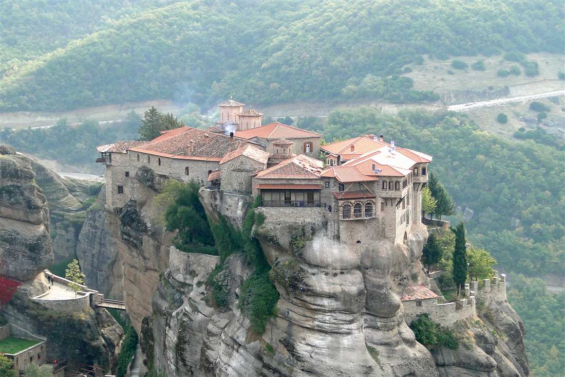 The Varlaam monastery on its sandstone pillar above the wooded valley, the first view on a Meteora day trip from Ioannina.