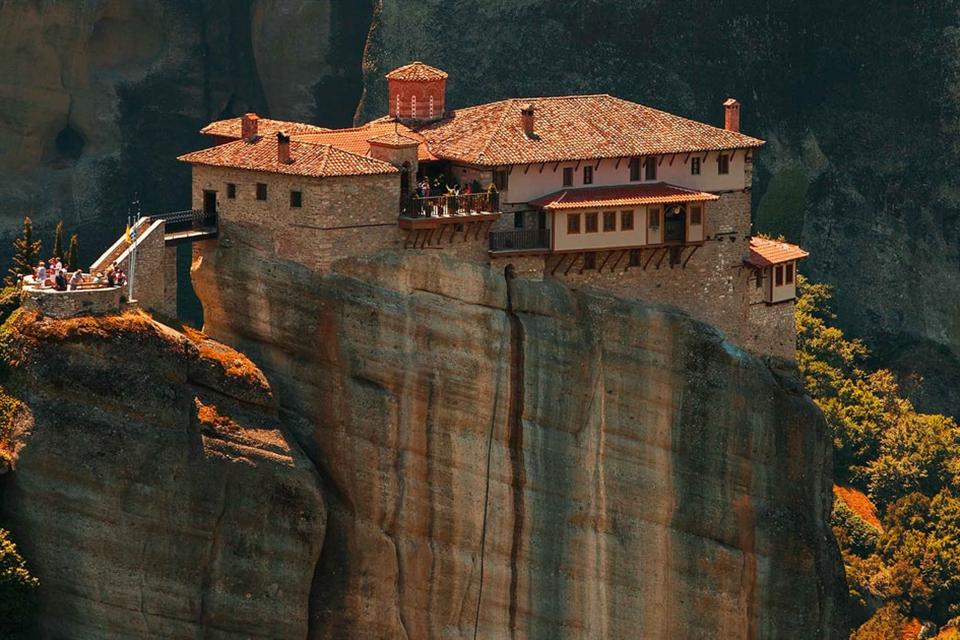 The Roussanou monastery of Meteora on top of a sheer sandstone pillar, framed by autumn trees.