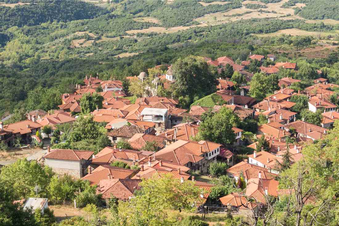 Red-tiled stone houses of Palaios Panteleimonas among green hills