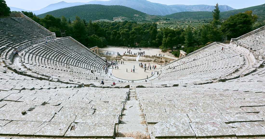 The stone tiers of the ancient theatre of Epidaurus curving around its round orchestra, with green hills behind.