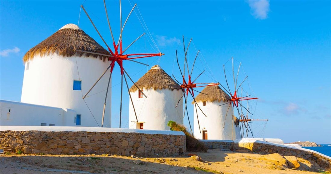 The white windmills of Mykonos on a low hill above the sea, a stop on the town walk before a Mykonos beer tasting.