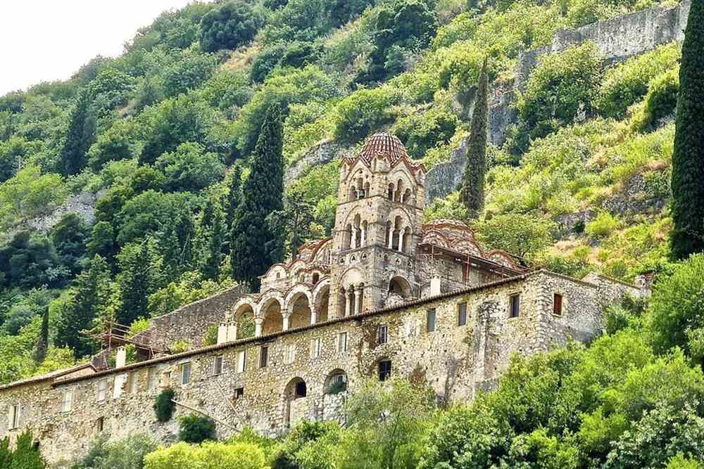 The Pantanassa monastery at Mystras, with its arched bell tower and stone walls on a green slope of Mount Taygetos.