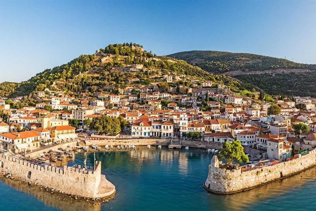 The round Venetian harbour of Nafpaktos with its stone walls and towers, below the castle hill and the red roofs of the town.