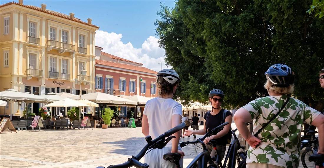 Riders in helmets with e-bikes in Syntagma Square in the old town of Nafplio.